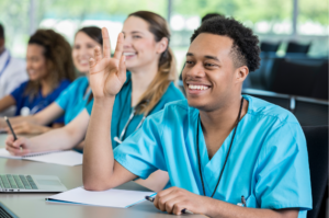 Male African American nursing student raising hand at table of fellow nursing students