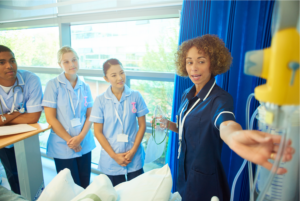 Female nurse showing nursing students an IV in a hospital room