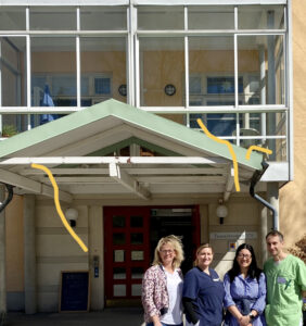 Two externs, graduate student Sarah McKiddy, and a staff member at the Sturby Nursing Home in Sweden stand outside the facility.